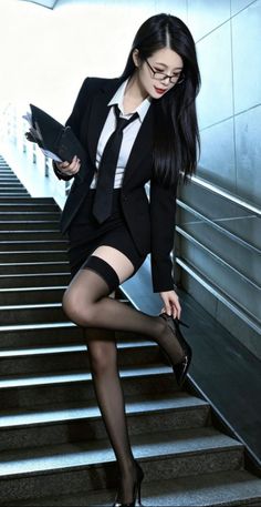 Woman in a business suit and stockings posing on stairs