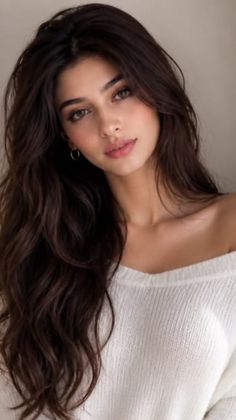 Woman with long dark hair wearing a white off-shoulder sweater