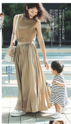 Woman in a pleated skirt and sleeveless top with a child outdoors
