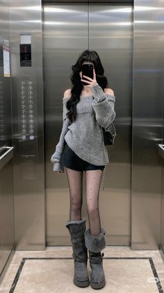 Woman in an off-shoulder sweater and polka dot tights taking a mirror selfie in an elevator