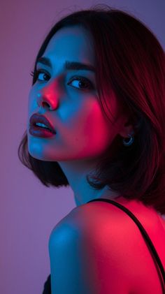 Woman with short hair in neon red and blue lighting looking over her shoulder