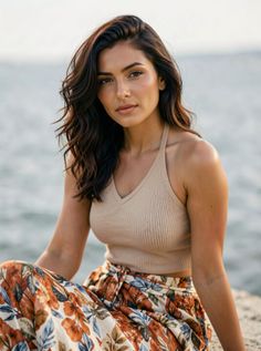 Woman with long wavy hair wearing a halter top and floral pants outdoors