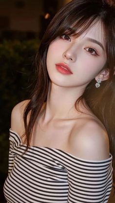 Woman with long hair wearing a striped off-shoulder top and earrings