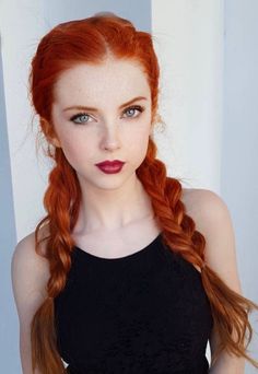 Woman with red braided hair, freckles, and dark lipstick in a black top