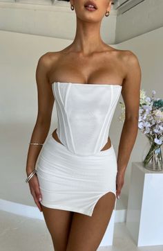 Woman in a white corset top and mini skirt with exposed skin