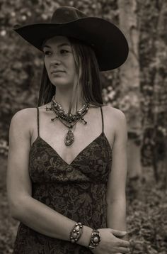 Woman in a cowboy hat and patterned dress with a large necklace outdoors