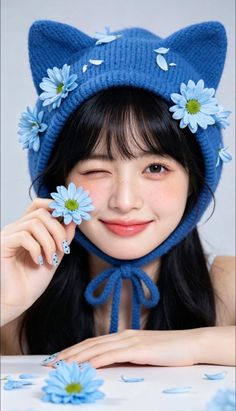 Woman in a blue cat-ear hat with blue flowers, winking with freckles
