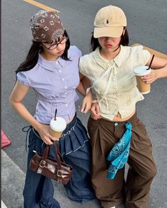Two young women in casual outfits holding iced coffee on a street