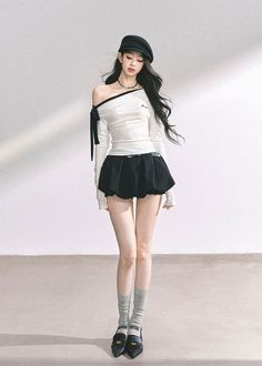 Woman with long black hair wearing a beret, off-shoulder top, and mini skirt