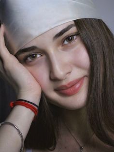 Woman with long brown hair and a white headscarf, smiling softly