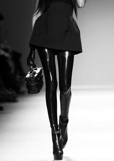Model in latex leggings and a mini skirt walking on a runway