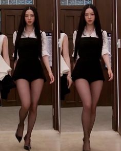 Woman with long black hair in a black dress and white shirt walking indoors