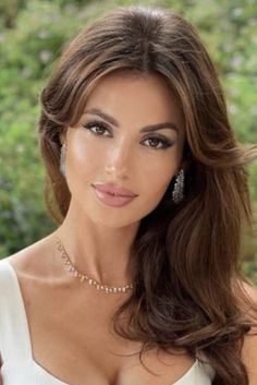 Woman with long brown hair and jewelry, showing cleavage