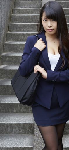 Woman in a navy suit and black tights holding a handbag on stairs