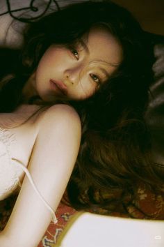 Woman with long dark hair lying down in a lace top with exposed shoulder