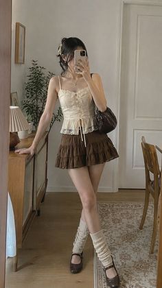 Woman in a lace top and ruffle skirt taking a mirror selfie indoors