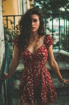 Woman in a red floral dress with long curly hair outdoors