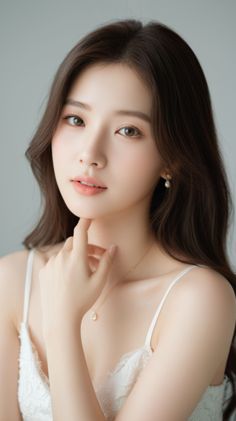 Woman with long brown hair wearing a white top and delicate jewelry