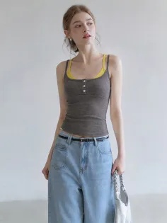 Woman in a gray tank top and light wash wide leg jeans holding a white bag