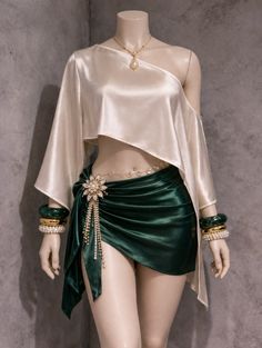 Mannequin displaying a silk top, green skirt, and elaborate jewelry