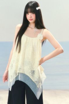 Woman with long black hair wearing a lace top and wide leg pants outdoors