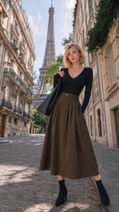 Woman in a midi skirt and long sleeve top on a cobblestone street with the Eiffel Tower