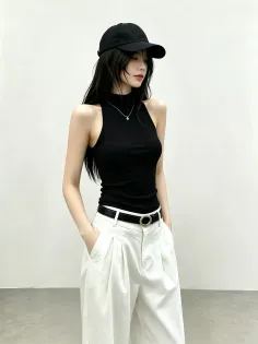 Woman in a black tank top, white wide-leg pants, and a black cap