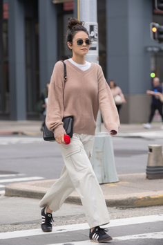 Woman in an oversized sweater and cargo pants crossing a city street