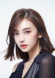 Woman with short brown hair wearing a black top and earrings