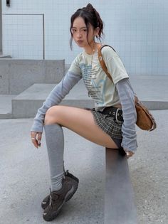 Woman in a plaid skirt and long sleeve shirt sitting outdoors