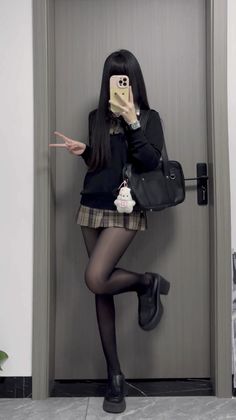 Person in a school uniform taking a mirror selfie with a peace sign
