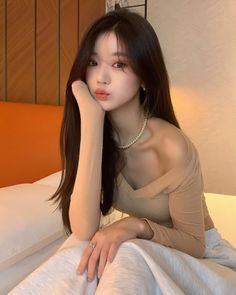 Woman with long dark hair wearing a pearl necklace and off-shoulder top