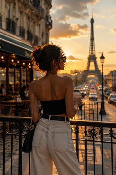 Woman in a strapless top and jeans looking at the Eiffel Tower at sunset