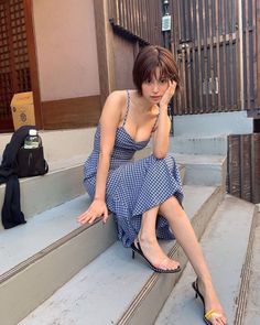 Woman in a blue gingham dress sitting on outdoor steps