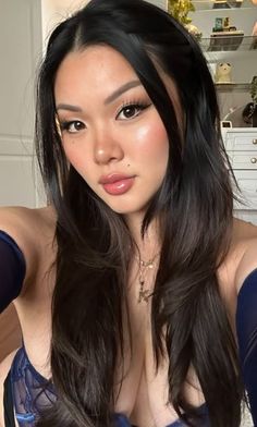 Woman with long dark hair wearing blue lingerie and jewelry indoors