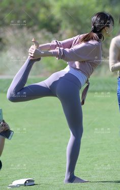Woman in athletic wear performing a yoga pose on green grass
