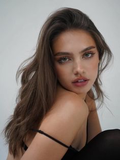 Woman with long brown hair and a dropped strap looking over her shoulder