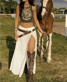 Woman in a crop top and long skirt with a horse outdoors