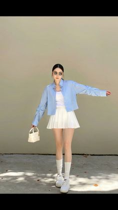 Woman in a white pleated skirt and blue striped shirt posing outdoors