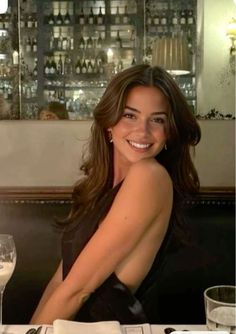 Smiling woman with long hair in a black dress at a restaurant