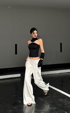 Woman in a black halter top and white wide-leg pants with exposed midriff