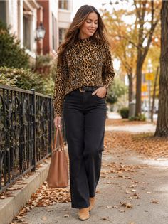 Woman in a leopard print top and black jeans walking on a street with autumn leaves