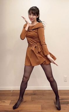 Woman in a brown dress and black tights posing indoors
