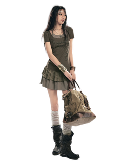 Woman with long dark hair wearing a layered outfit and holding a large bag