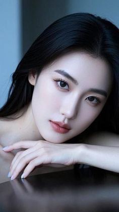 Woman with long black hair and bare shoulders resting her head on her hands