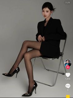 Woman in a black blazer and sheer stockings sitting on a chair