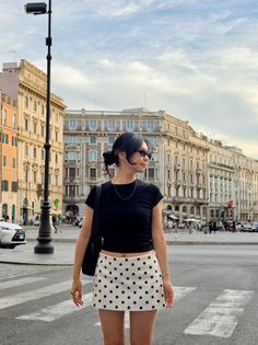 Woman in a black crop top and polka dot skirt on a city street