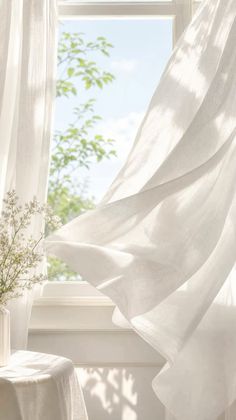 White curtains blowing in the breeze with sunlight streaming through a window