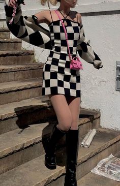 Woman in a black and white checkered dress and long boots outdoors