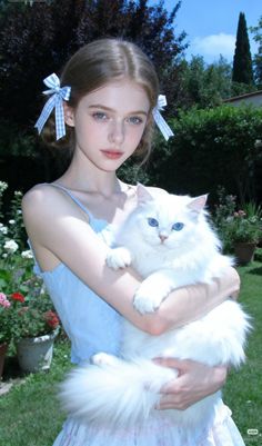 Young woman with blue eyes holding a white cat in a garden